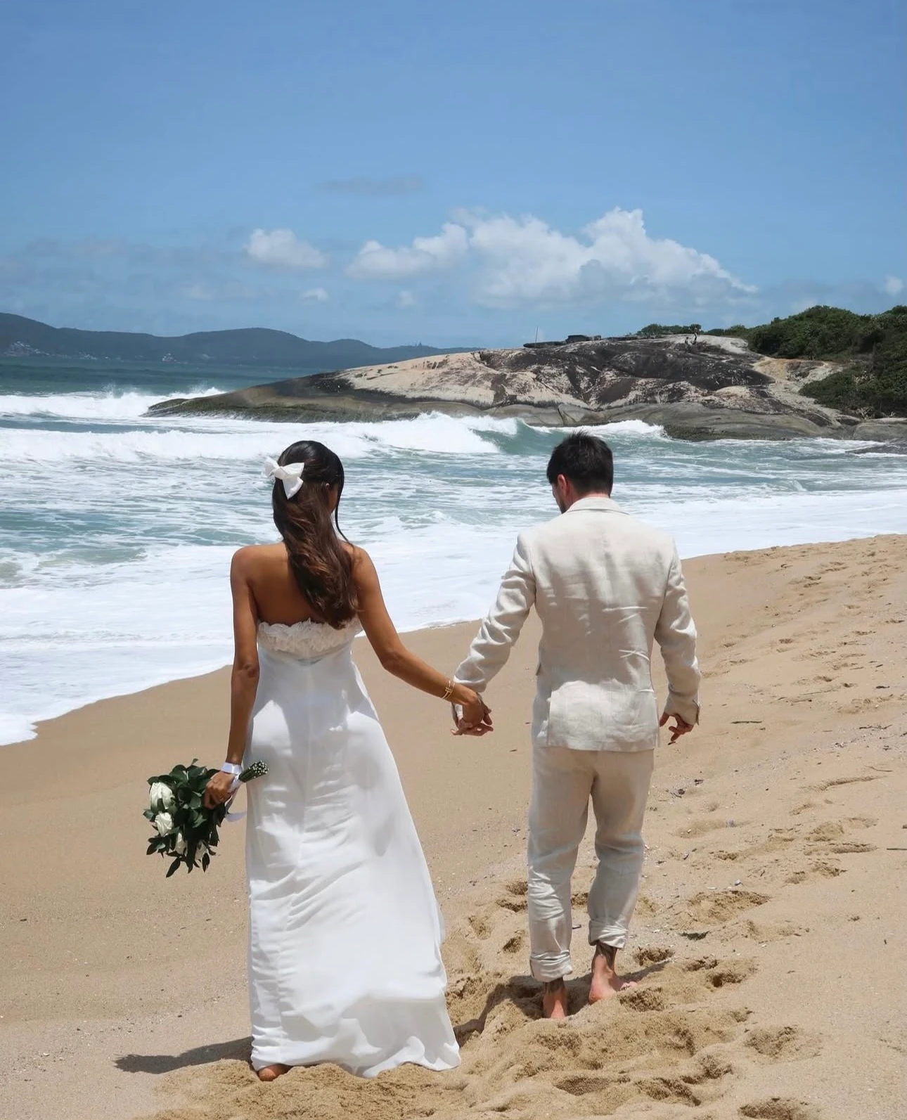 Lua de mel: um casal de mãos dadas na praia