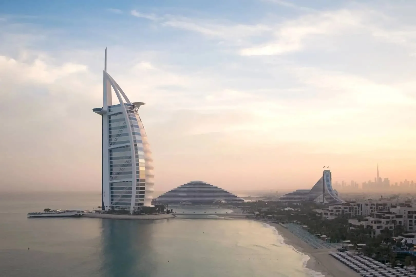 Burj Al Arab em forma de vela junto ao mar sob luz suave do amanhecer